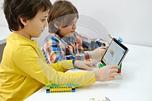 Multi ethnic children at technology lesson coding robot on tablet