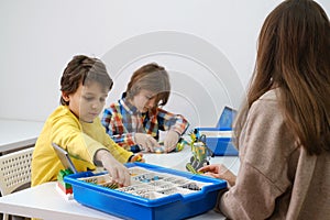 Multi ethnic children at technology lesson coding robot on tablet