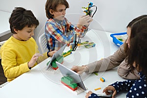 Multi ethnic children at technology lesson coding robot on tablet