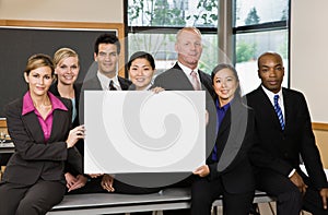 Multi-ethnic co-workers posing with blank sign