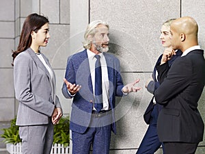 Multi-ethnic corporate executives standing talking in lobby of m