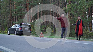 Multi ethnic couple on the background of a broken vehicle standing on the side of the road. Handsome asian man holding