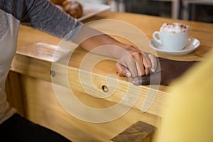 Multi ethnic couple holding hands in coffee house