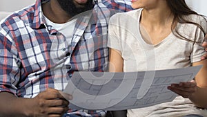 Multi-ethnic couple looking at project and planning design of new apartment