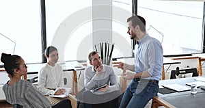 Multi ethnic employees listen team leader engaged in briefing