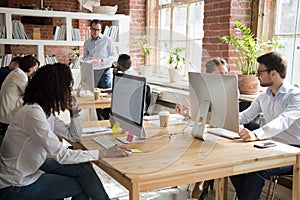 Multi-ethnic employees working on computers in modern office room