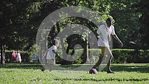 Multi ethnic family in the park. Mom blonde and African American husband play football with her son.