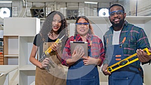 Multi ethnic family working in a wooden furniture factory. Short black hair dad holding water level gauge ruler. Mom holding