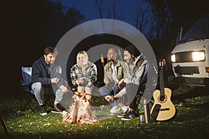 Multi ethnic friends having picnic by fireplace