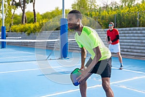 Multi-ethnic friends playing pickleball together in a sunny day