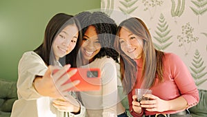 Multi-ethnic friends smiling taking a selfie indoors