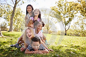 Multi-ethnic group of children lying in a pile in a park photo