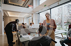 A multi-ethnic group of colleagues interacts in a bright, open-plan workspace, exemplifying teamwork and collaboration.