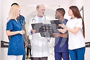 multi-ethnic group of doctors talking in hospital hallway examining x-ray scans together