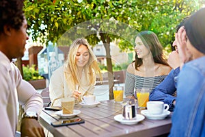 Multi-ethnic group of friends having a drink together in an outdoor bar.