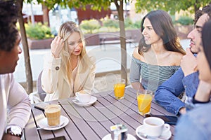 Multi-ethnic group of friends having a drink together in an outdoor bar.