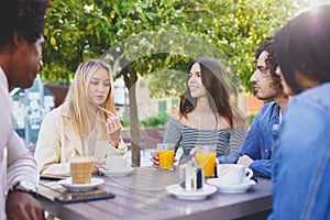 Multi-ethnic group of friends having a drink together in an outdoor bar.