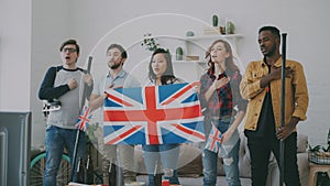 Multi ethnic group of friends listening and singing British national anthem before watching sports championship on TV