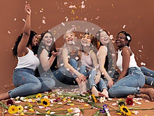 Multi ethnic group of happy women sitting under falling petals photo