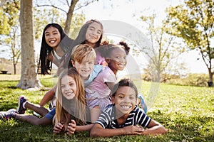 Multi-ethnic group of kids lying on each other in a park