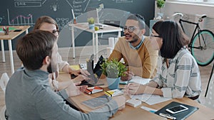 Multi-ethnic group of people doing high-five talking and laughing in creative shared office