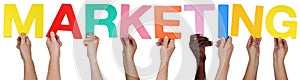 Multi ethnic group of people holding the word marketing