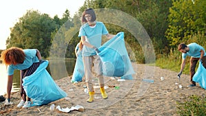 Multi-ethnic group of students collecting garbage from beautiful lake beach