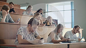 Multi ethnic group of students using smartphones during the lecture. Young people using social media while studying in