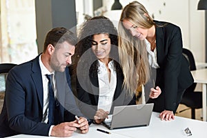 Multi-ethnic group of three businesspeople meeting in a modern o