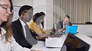 Multi-ethnic group of young business people sitting at the table on conference in the meeting room. A group of mixed