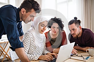 A multi-ethnic group of young friends with laptop indoors, house sharing concept.