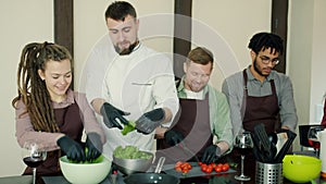 Multi-ethnic group of young people cooking salad during cookery master-class