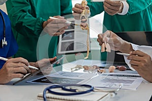 A multi-ethnic medical team is meeting with doctors in white lab coats and surgical gowns who sit at tables