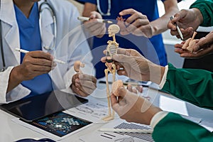 A multi-ethnic medical team is meeting with doctors in white lab coats and surgical gowns who sit at tables