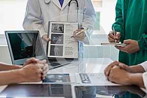 A multi-ethnic medical team is meeting with doctors in white lab coats and surgical gowns who sit at tables