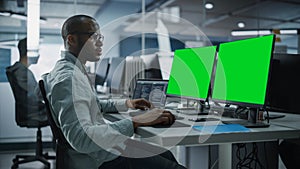 Multi-Ethnic Office: Black IT Programmer Working on Computer with Green Screen Chroma Key Display