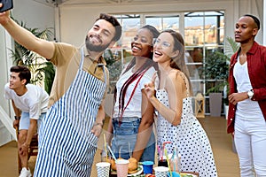 Multi ethnic people group enjoying paty at backyard, take photo on smartphone