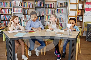 Multi-ethnic pupils study and write at table in library or classroom. Back to school