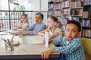Multi-ethnic pupils study and write at table in library or classroom. Back to school