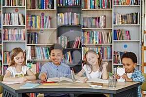 Multi-ethnic pupils study and write at table in library or classroom. Back to school