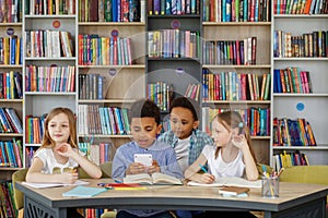 Multi-ethnic pupils study and write at table in library or classroom. Back to school