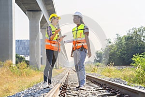 multi ethnic railway construction workers working outdoors,standing at rail tracks,discuss work