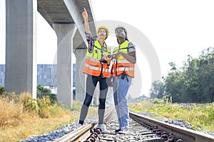 multi ethnic railway construction workers working outdoors,standing at rail tracks,discuss work