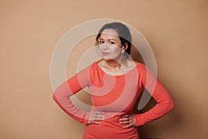 Multi-ethnic amazed pretty woman looking at camera with stupefaction, asking what, looking at camera, beige background photo