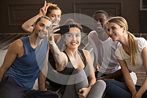 Multi-ethnic sporty people having fun taking group selfie in gym