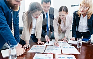 Multi-ethnic team of business people analyzing charts with statistics