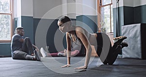 Multi ethnic Woman doing timed floor workout in gym.