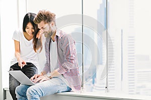 Multi-ethnic young couple or college student using notebook laptop together in campus or office. Information technology concept