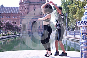 Multi-ethnic young couple doing figures while dancing bachata sensually outdoors