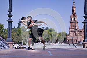 Multi-ethnic young couple doing figures while dancing bachata sensually outdoors